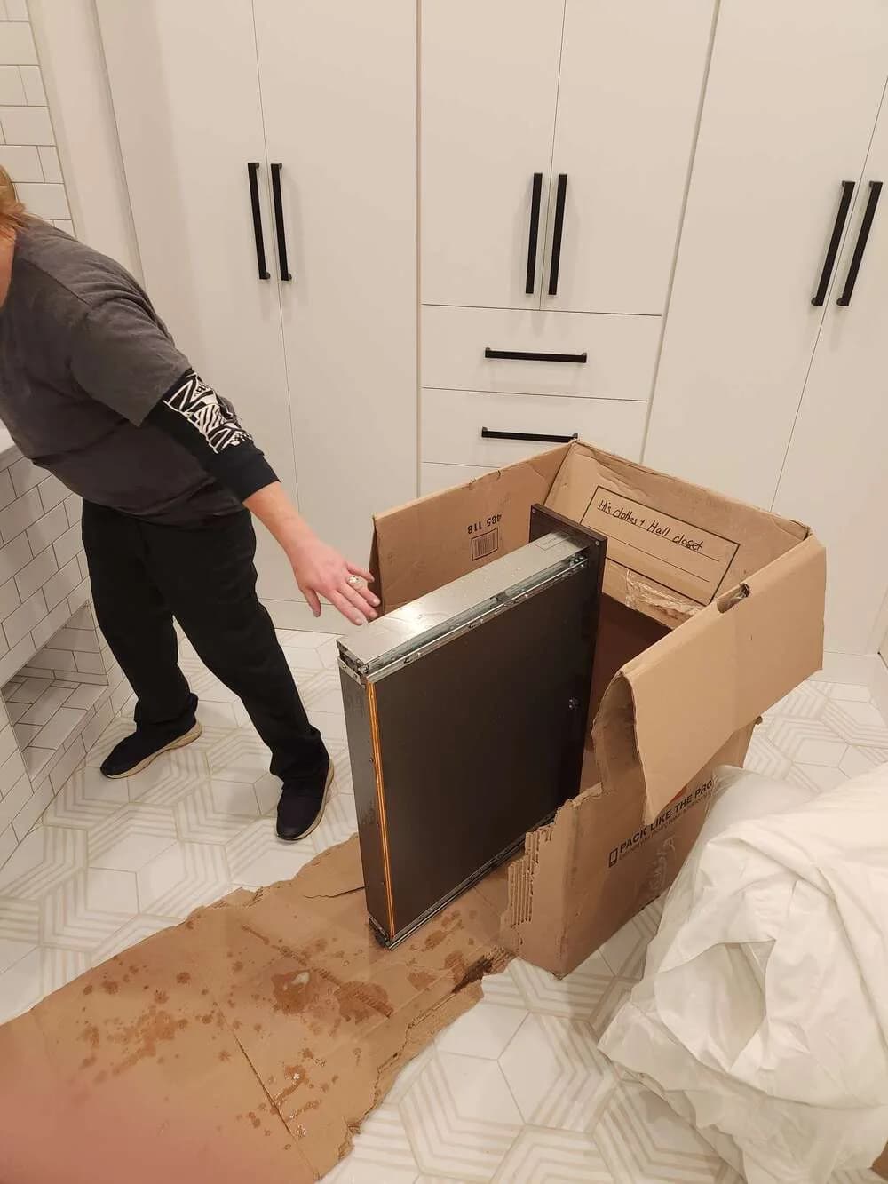 Technician pulling out kitchen cabinets to clean the dust and grime behind them