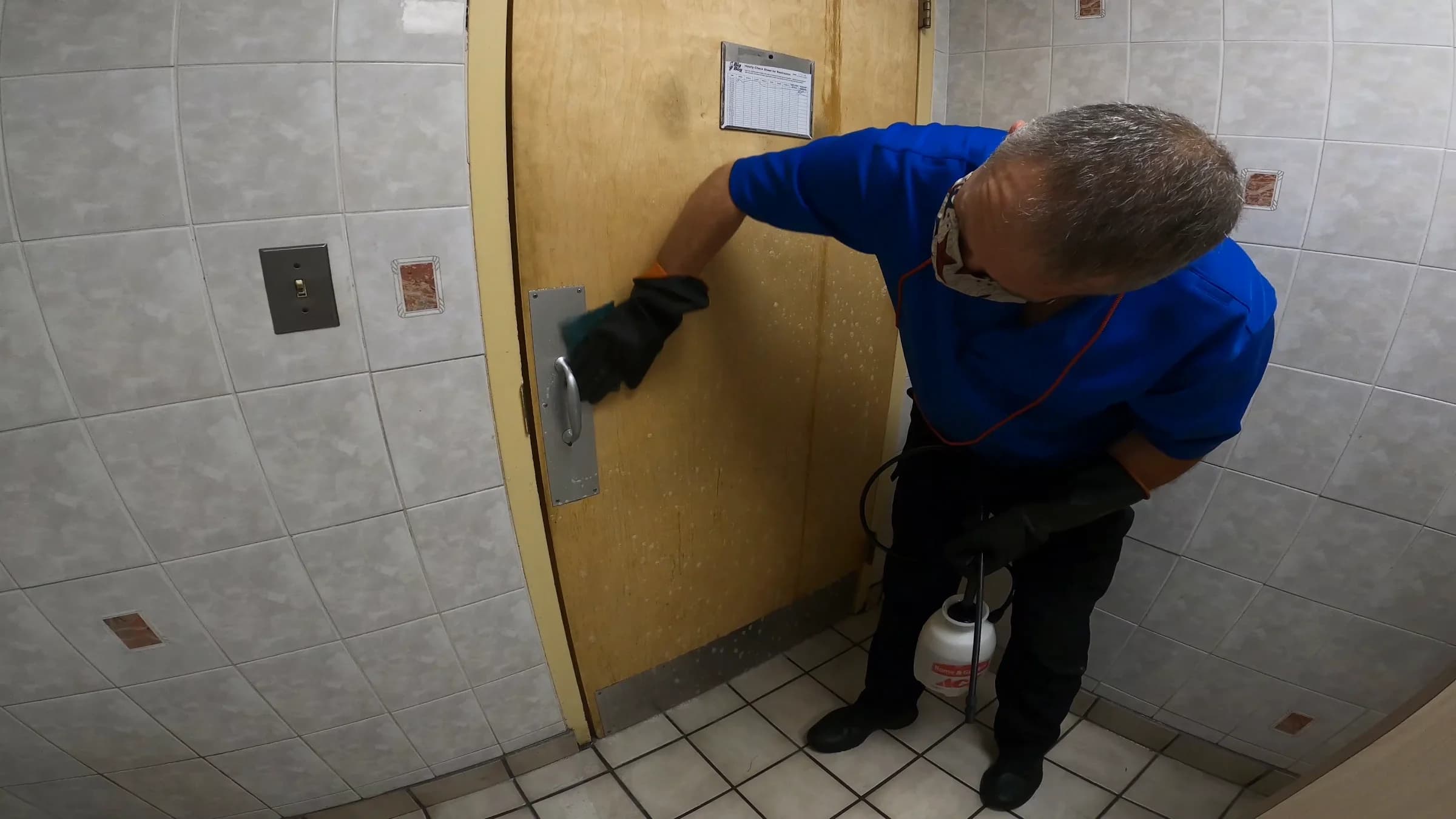 SWAT technician scrubbing down a weathered entry door by hand