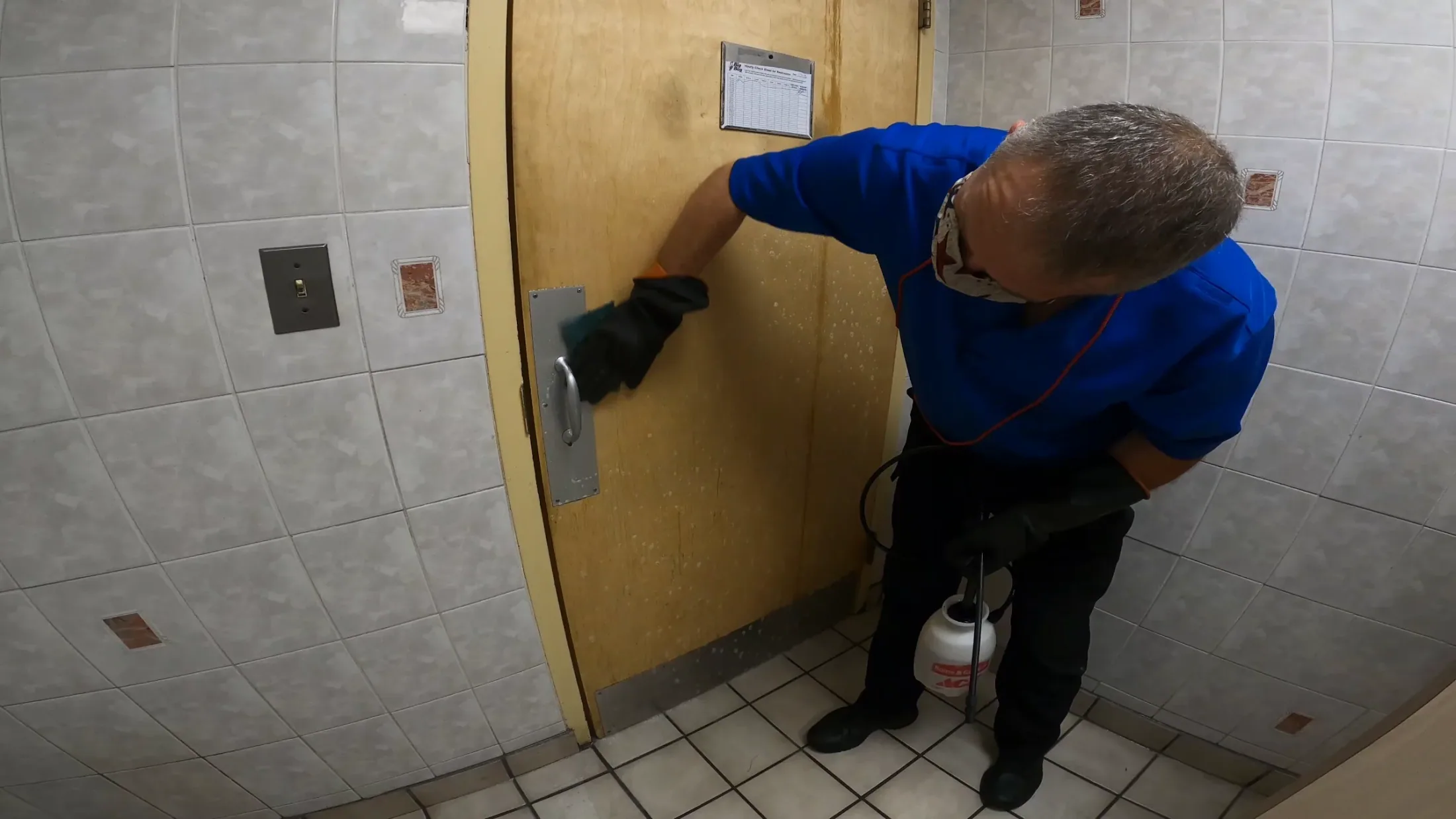 SWAT technician scrubbing down a weathered entry door by hand