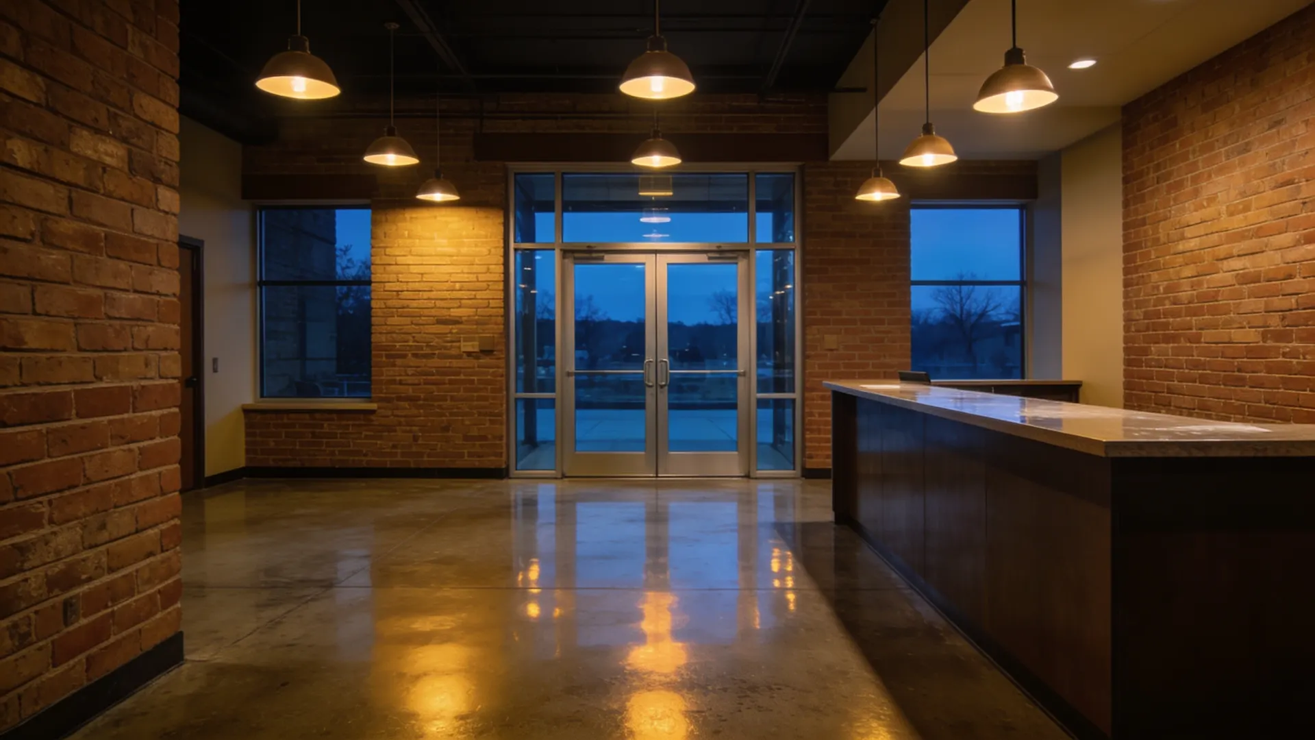Commercial lobby at dusk after an evening clean, polished concrete floor reflecting the pendant lights
