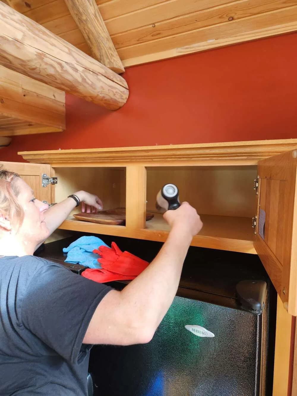 Technician with a flashlight inspecting above kitchen cabinets