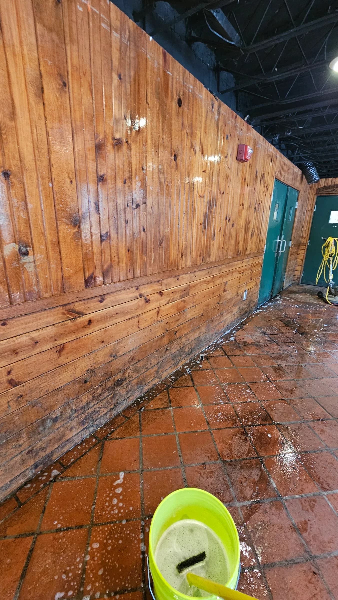 Wood-paneled hall before restoration, floor covered in debris and stains