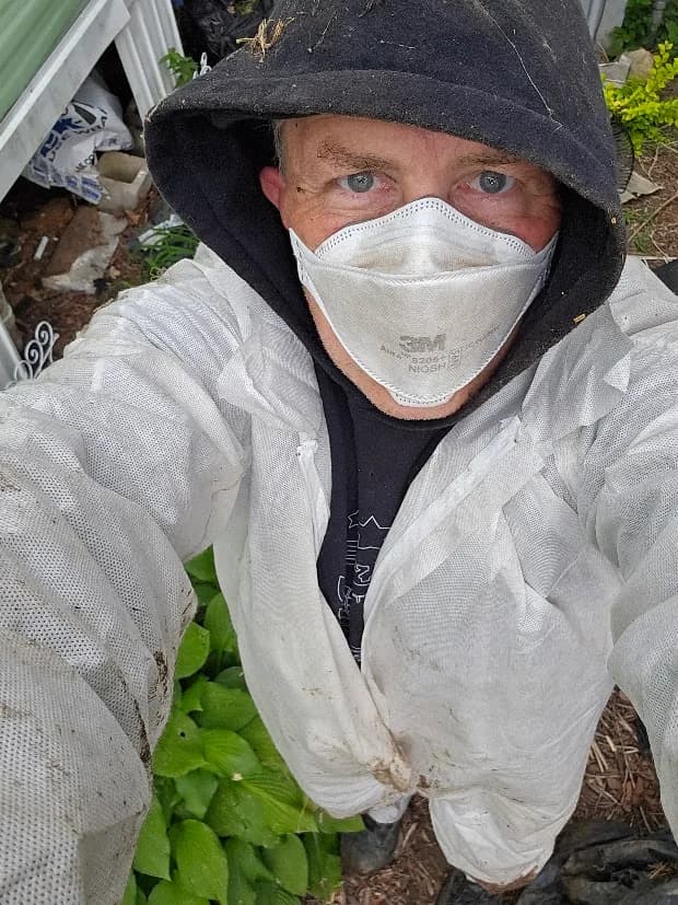 Matt Castle wearing a white protective coverall and face mask during work