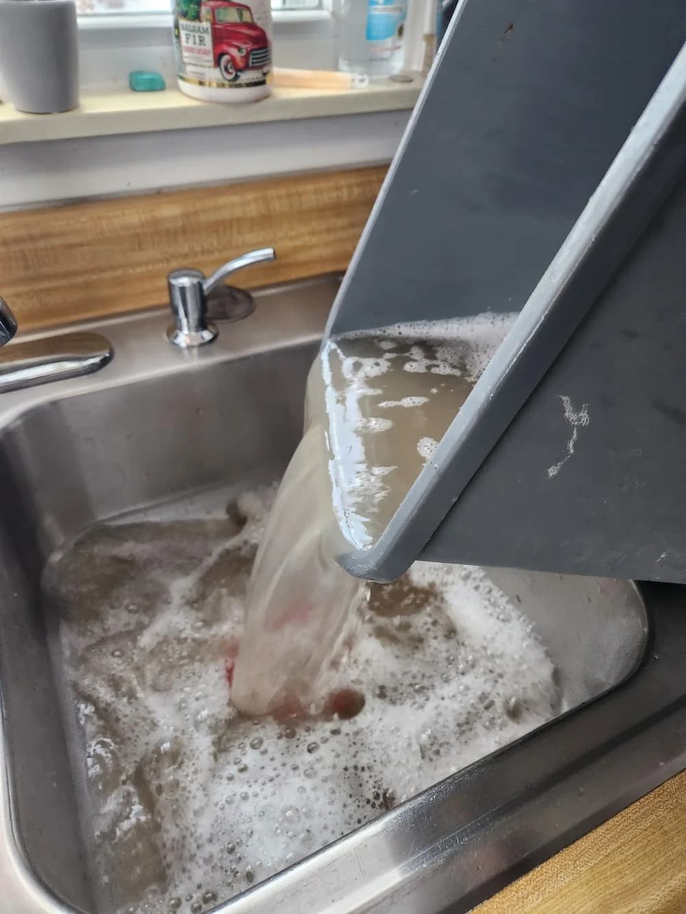 Commercial sink being scrubbed to bare metal with foaming degreaser