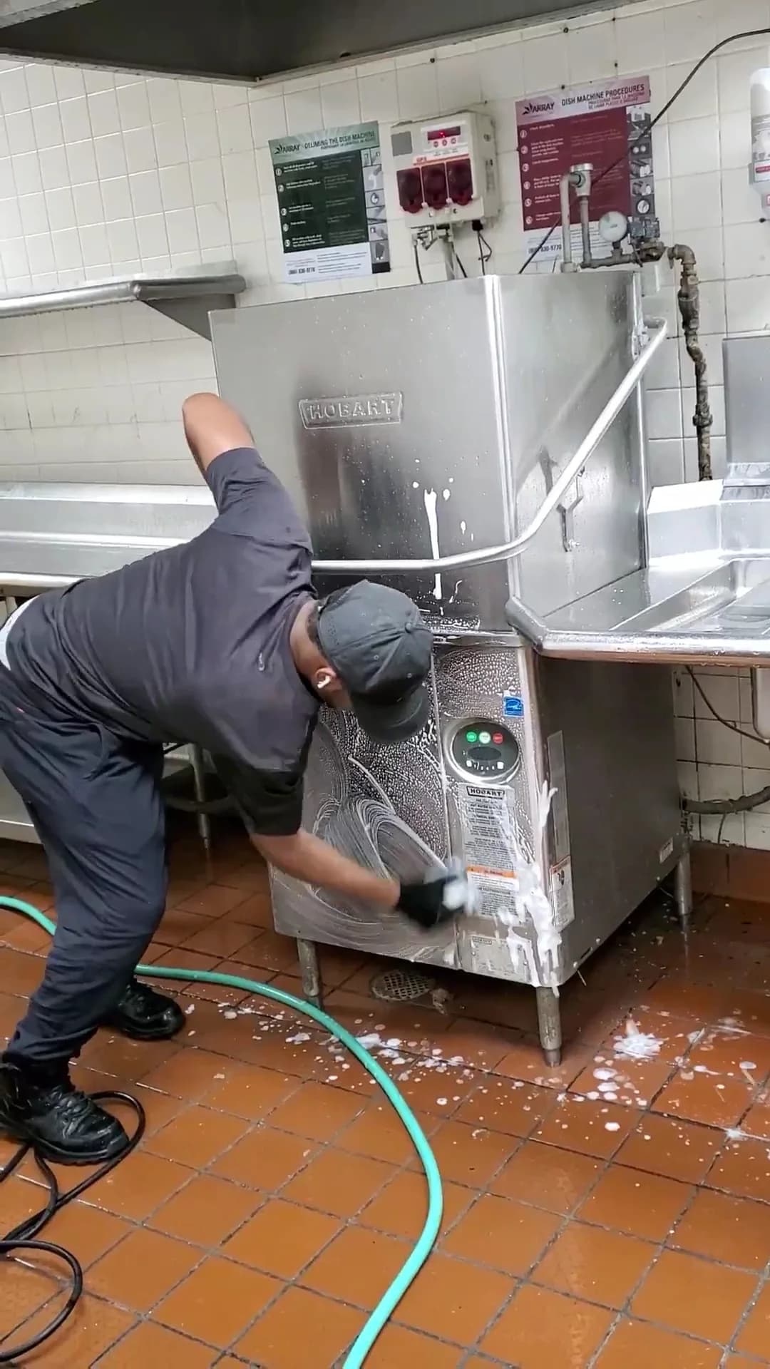 Technician cleaning a commercial dishwasher exterior