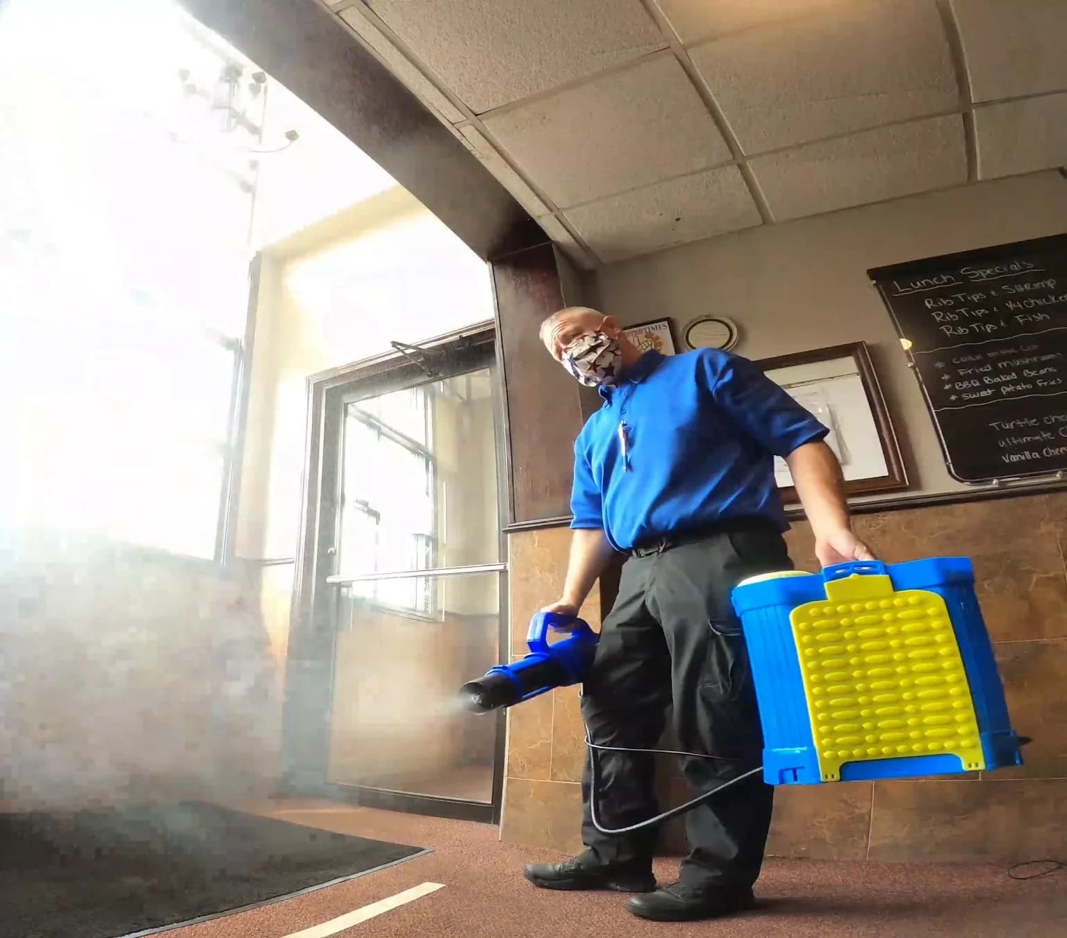 Technician with spray equipment in a shaft of window light